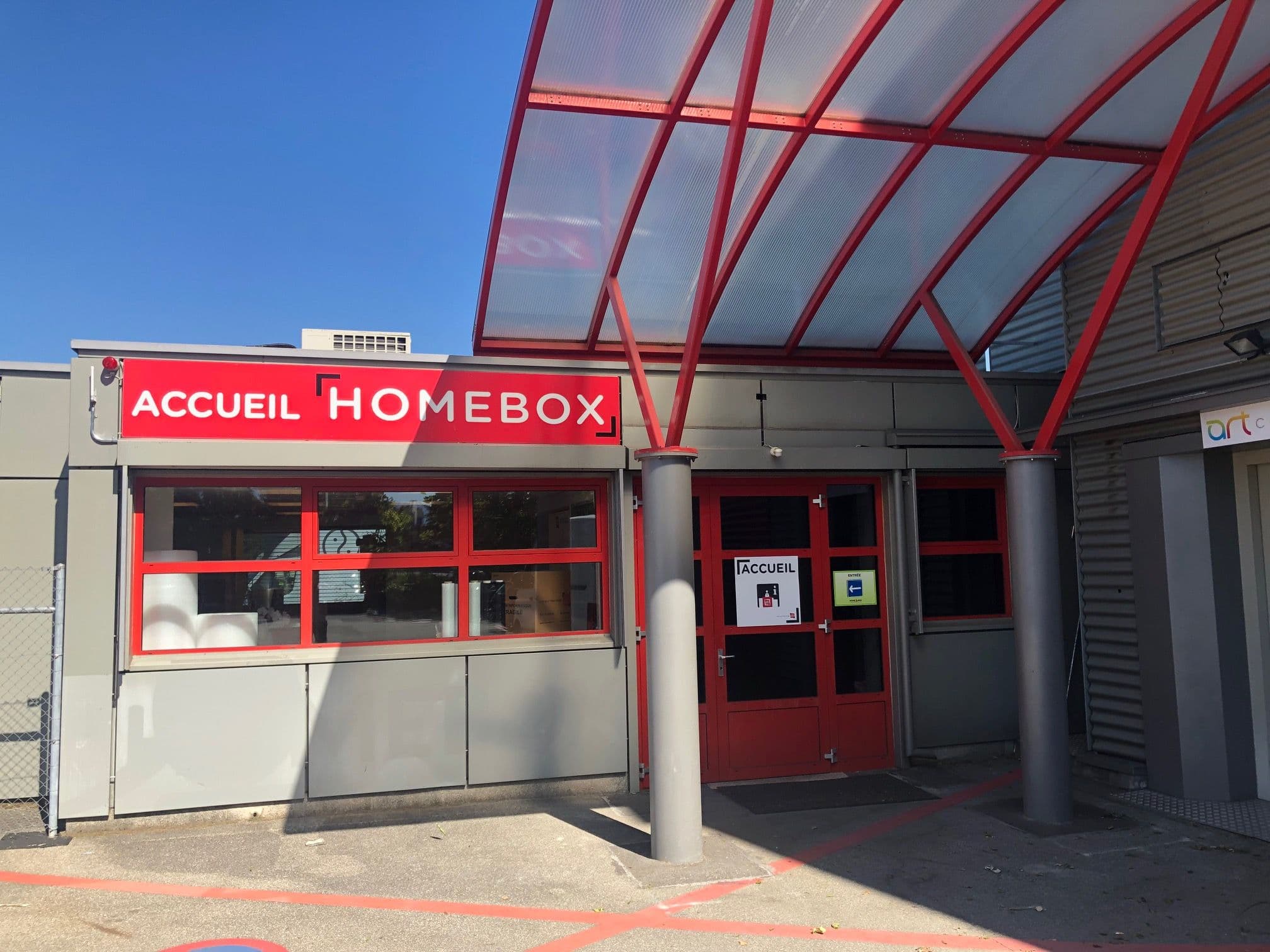 Accueil du centre HOMEBOX Genève avec comptoir rouge et gris et logo HOMEBOX.
